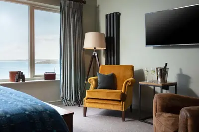 a hotel room with a chair and a television at The Lewinnick Lodge in Newquay
