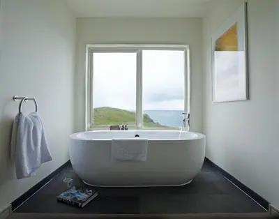 a bath tub in a bathroom with a large window at The Lewinnick Lodge in Newquay