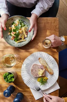 a table with two plates of food and glasses of wine at The Lewinnick Lodge in Newquay