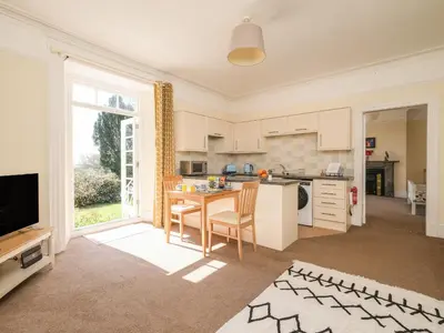 a kitchen and living room with a table and a television at The Patio Flat in Bodmin