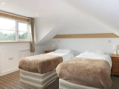 two beds in a room with white walls and a window at Crift Farm Cottage in Bodmin