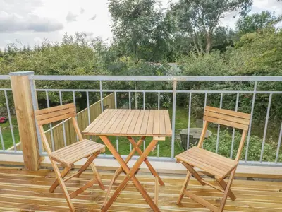 a wooden table and two chairs on a deck at Crift Farm Cottage in Bodmin
