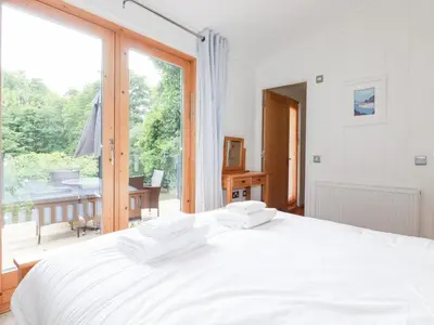 a bedroom with a white bed and a large window at 6 Water's Edge in Looe