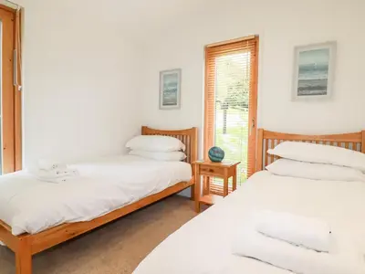 two beds in a room with a window at 6 Water's Edge in Looe
