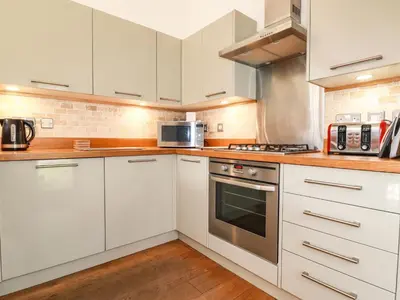 a kitchen with white cabinets and stainless steel appliances at 4 Water's Edge in Looe