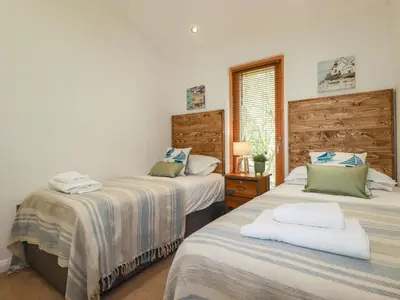 a bedroom with two beds and a window at 4 Water's Edge in Looe