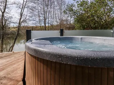 a jacuzzi tub on a wooden deck at 4 Water's Edge in Looe