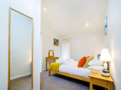 a bedroom with a bed and a mirror at 2 Water's Edge in Looe