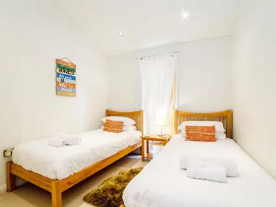 two beds in a room with white walls at 2 Water's Edge in Looe