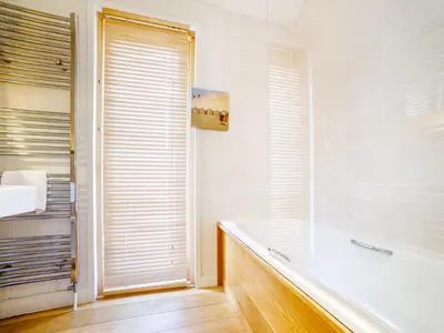 a bathroom with a bath tub and a window at 2 Water's Edge in Looe