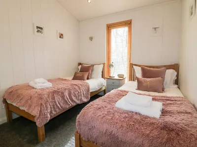 a bedroom with two beds and a window at 9 Stonerush Valley in Looe