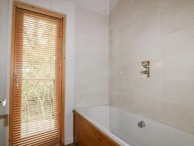 a white bathroom with a tub and a window at 9 Stonerush Valley in Looe