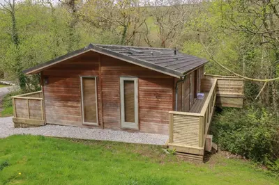 a small wooden cabin with a porch in the grass at 2 Stonerush Valley in Looe