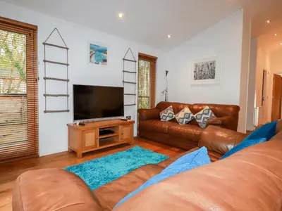 a living room with a couch and a flat screen tv at 2 Stonerush Valley in Looe