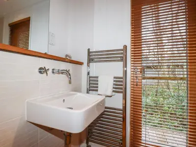 a white sink in a bathroom with a window at 2 Stonerush Valley in Looe