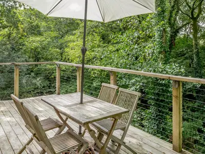 a wooden table and chairs with an umbrella on a deck at 8 Streamside in Looe
