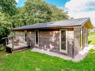 a wooden cabin with a deck in the grass at 8 Streamside in Looe