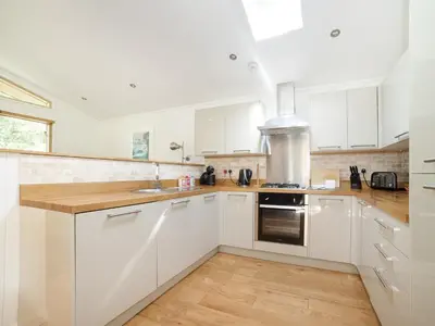 a white kitchen with white cabinets and a sink at 7 Streamside in Looe