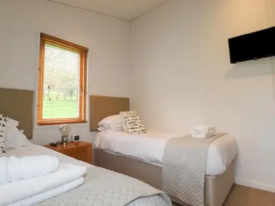 a room with two beds and a tv and a window at 7 Streamside in Looe