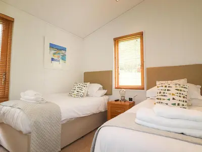 two beds in a room with white walls and windows at 7 Streamside in Looe
