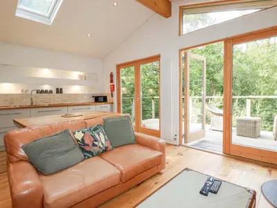 a living room with a leather couch and a kitchen at 4 Stonerush Valley in Looe