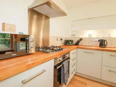 a kitchen with a stove and a microwave at 4 Stonerush Valley in Looe