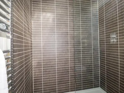 a bathroom with a shower with brown tiled walls at 4 Stonerush Valley in Looe