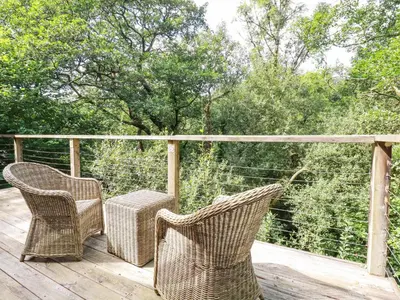 two wicker chairs and a table on a wooden deck at 4 Stonerush Valley in Looe