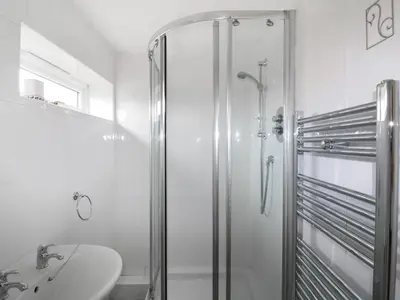 a white bathroom with a shower and a sink at Sheila's Cottage in Penryn