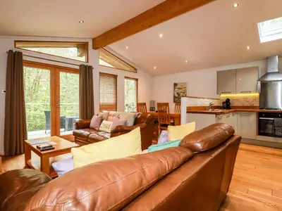 a living room with a leather couch and a kitchen at 6 Streamside in Looe