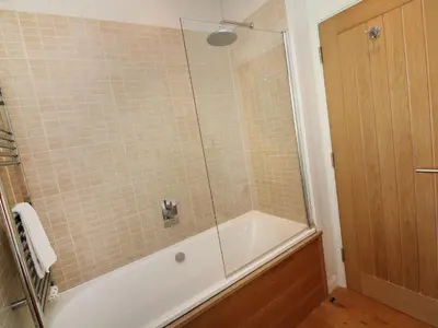a bathroom with a tub and a shower with a glass door at 6 Streamside in Looe