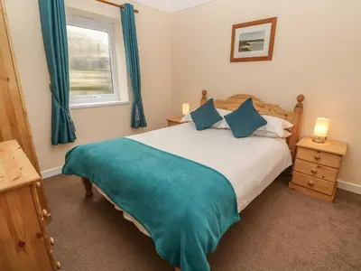a bedroom with a bed with blue curtains and a window at Treleigh in Hayle