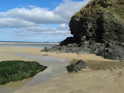 a sandy beach with a large rock and the ocean at Treleigh in Hayle