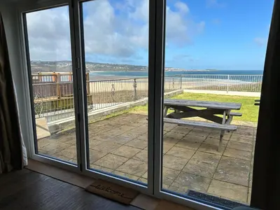 a view of the ocean from a window with a picnic table at Treleigh in Hayle