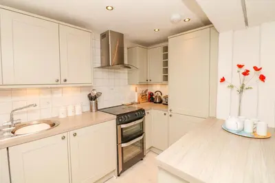 a kitchen with white cabinets and a sink at The Shell Seekers in Fowey