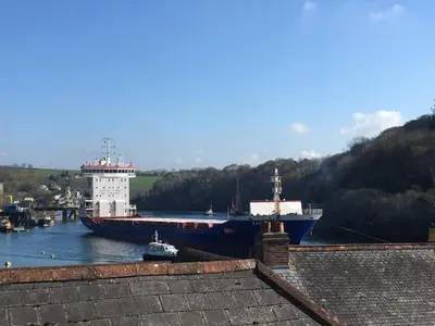 a large ship is docked in a river at The Shell Seekers in Fowey