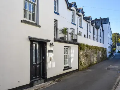 a white building with a black door on a street at Serendipity in Fowey