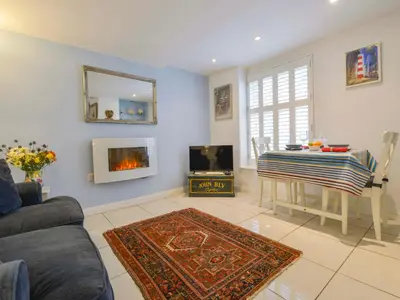 a living room with a couch and a table and a tv at Serendipity in Fowey