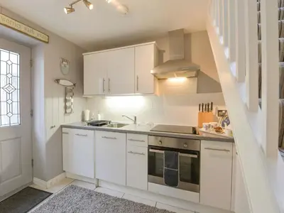 a kitchen with white cabinets and a sink at Serendipity in Fowey