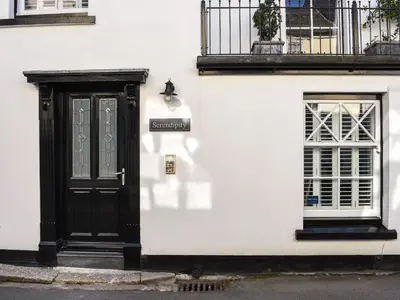 a white building with a black door and a window at Serendipity in Fowey