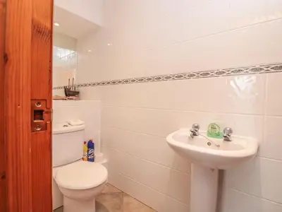 a white bathroom with a toilet and a sink at Sorrel Cottage in Padstow