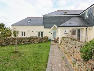 a white house with a stone wall and a stone path at Sorrel Cottage in Padstow