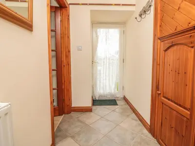 a hallway with a wooden door and a window at Sorrel Cottage in Padstow