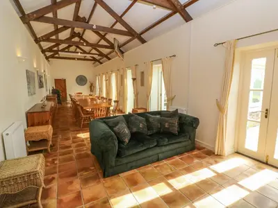 a living room with a green couch and a table at Tregoninny Vineyard and Woodland Farmhouse in Truro