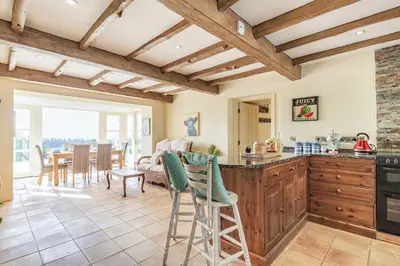 a kitchen with wooden ceilings and a dining room at Tregoninny Vineyard and Woodland Farmhouse in Truro