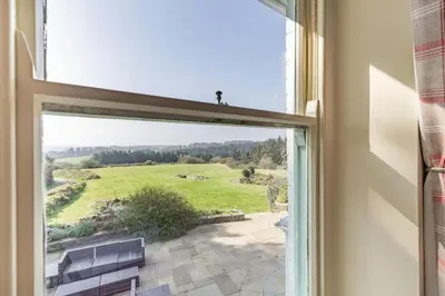 a window with a view of a green field at Tregoninny Vineyard and Woodland Farmhouse in Truro