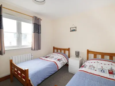 two twin beds in a room with a window at Jacks Mews in Tintagel
