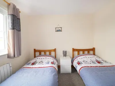 two twin beds in a room with a window at Jacks Mews in Tintagel
