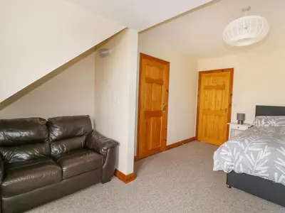 a living room with a leather couch and a bed at Jacks Mews in Tintagel
