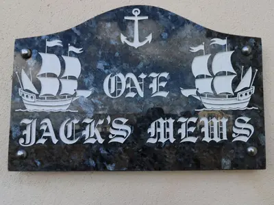 a sign on a wall with two boats on it at Jacks Mews in Tintagel